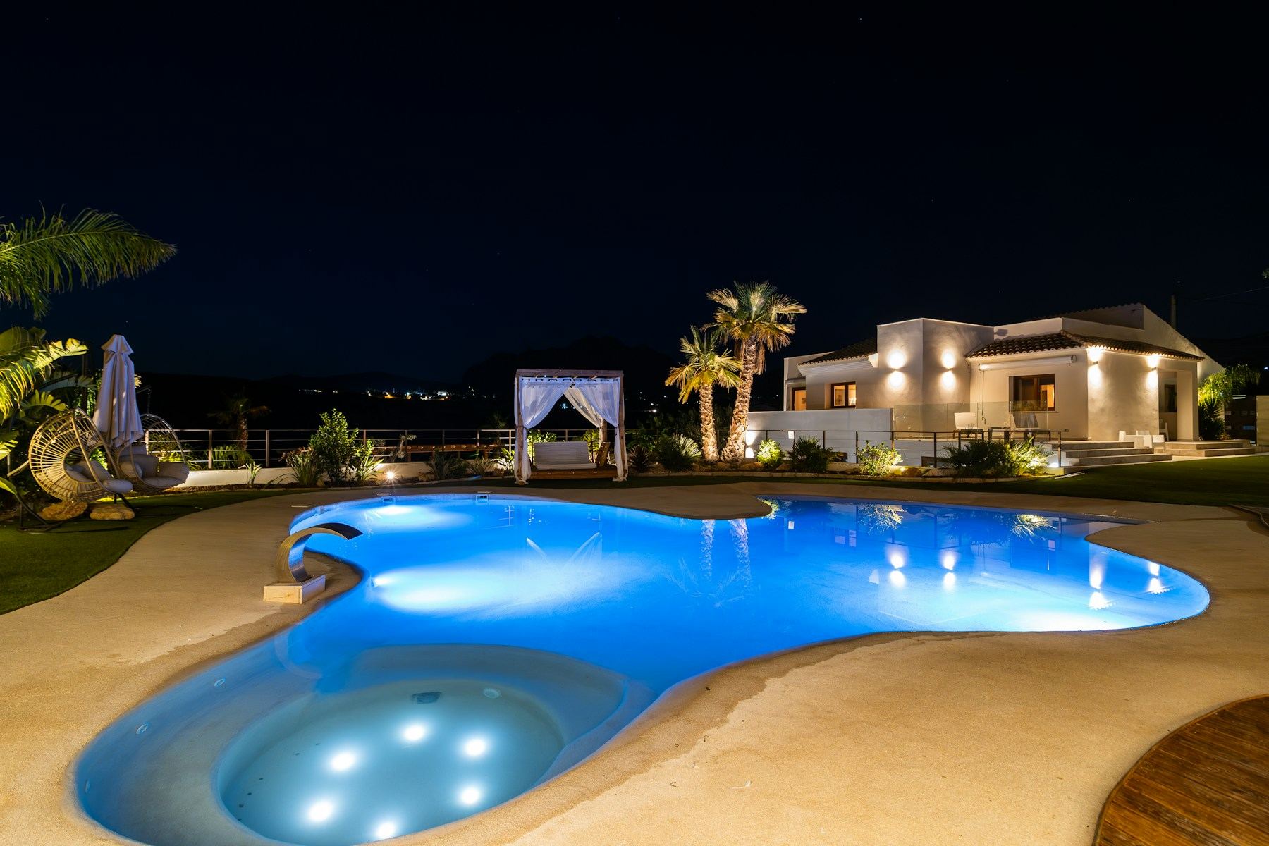 Villa and illuminated pool at night